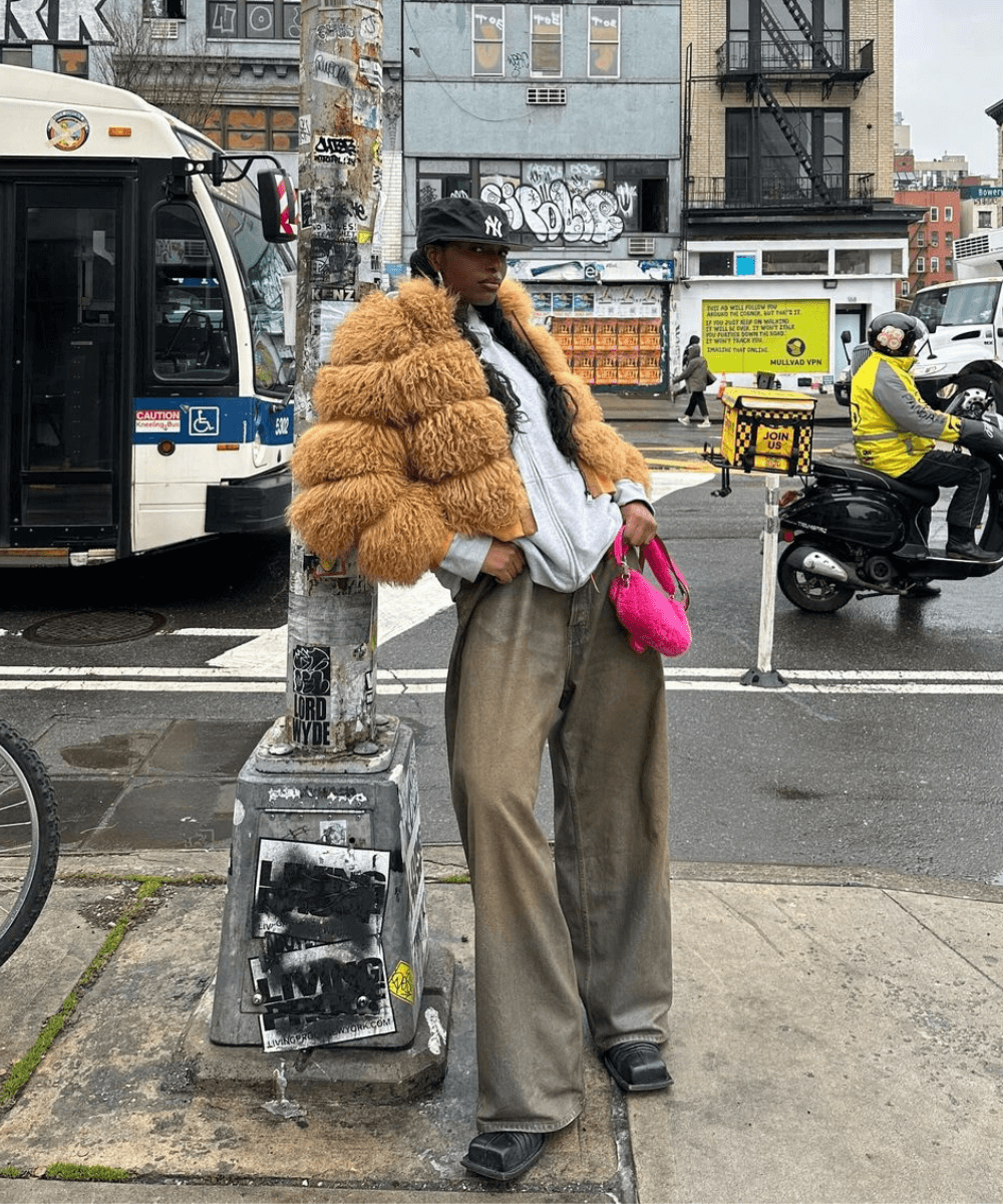Jessi Regina - calça jeans, blusa listrada e casaco de pelúcia - outono 2024 - inverno - mulher negra em pé na rua usando um boné - https://stealthelook.com.br