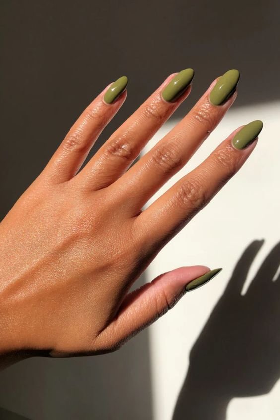 Unhas em gel amendoada pintadas com esmalte verde oliva, esmalte tendência de moda atual. O tom neutro e sofisticado é perfeito para todas as estações e combina com diversos estilos de vestuário. Beleza e elegância em destaque.