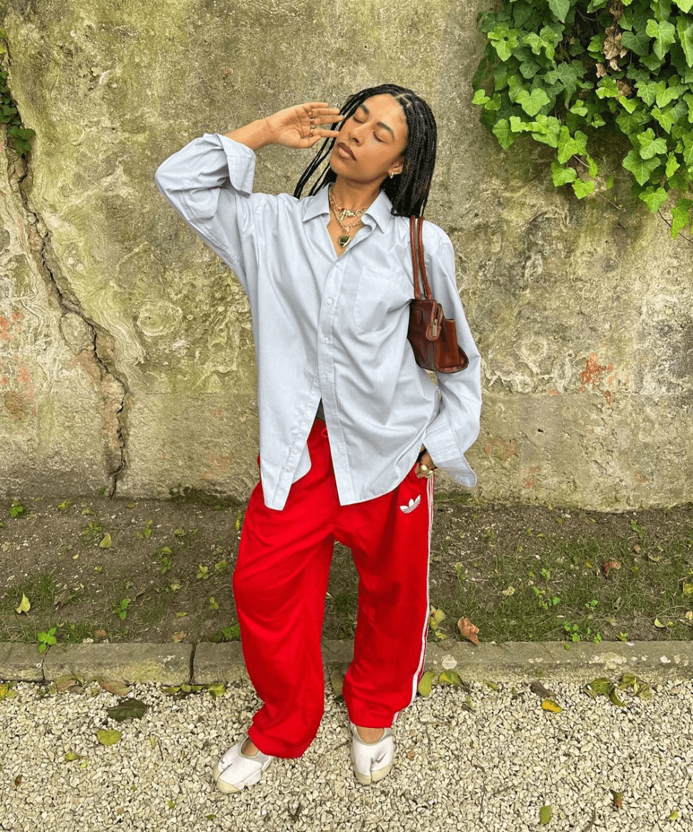 @hannahyohon - calça adidas vermelha, tênis e camisa social oversized - calça esportiva - outono - mulher negra de tranças em pé na rua - https://stealthelook.com.br