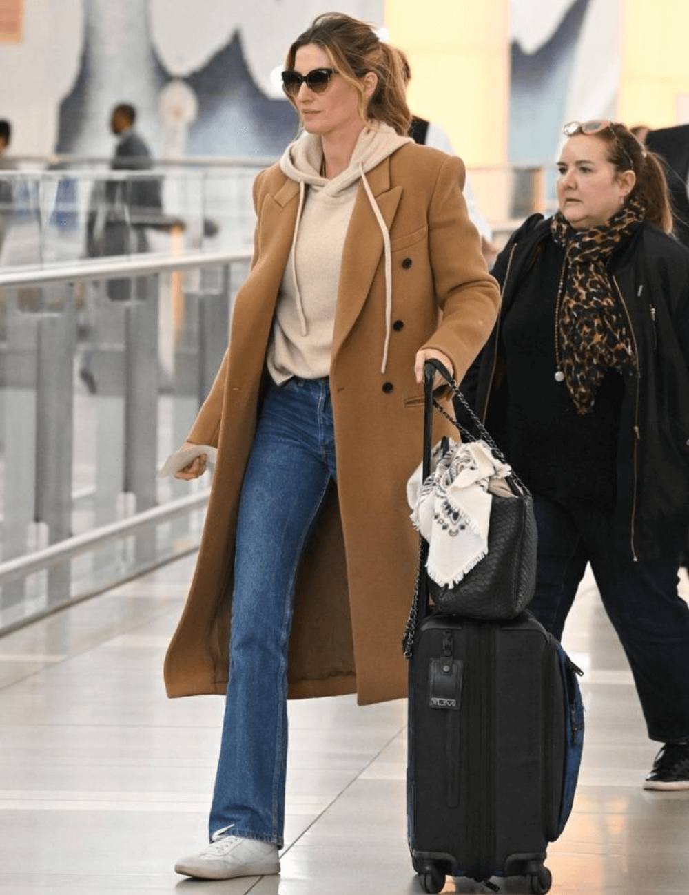 Gisele Bündchen - calça jeans, moletom bege e sobretudo caramelo - Gisele Bündchen - inverno - mulher de óculos andando em um aeroporto - https://stealthelook.com.br