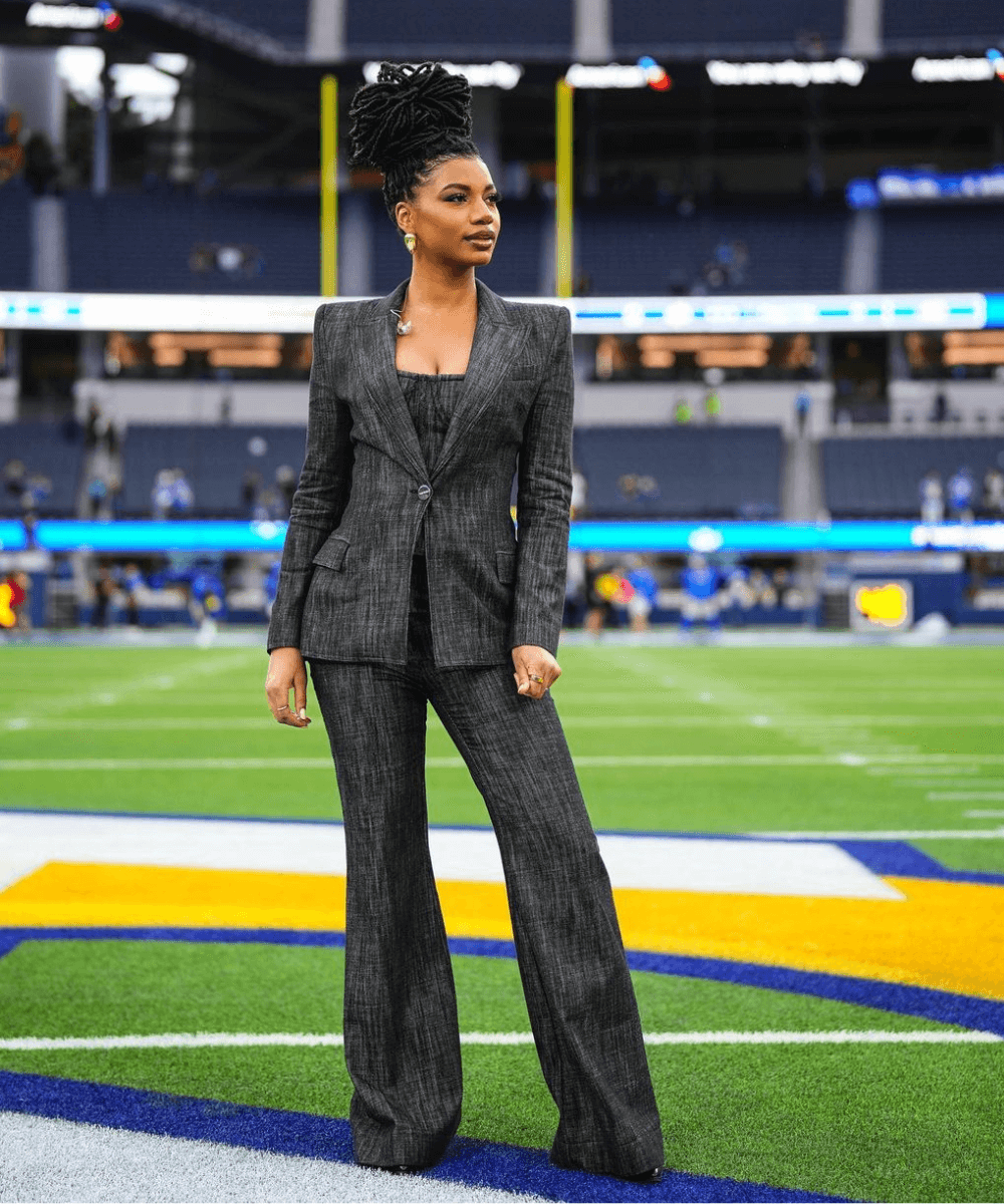 Taylor Rooks - conjunto preto de alfaiataria - Taylor Rooks - inverno - mulher negra em pé em um campo de futebol americano - https://stealthelook.com.br