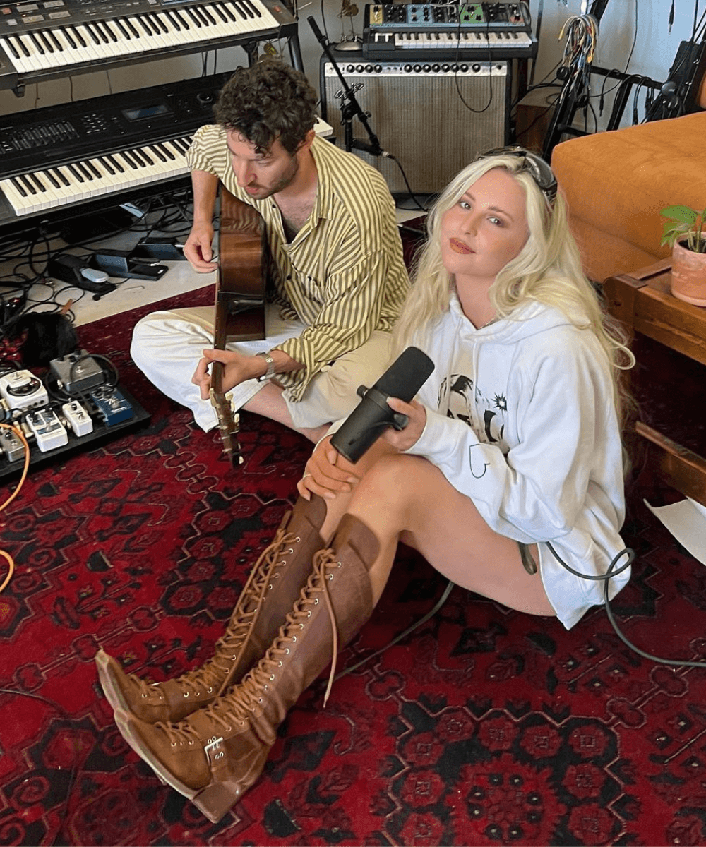 Laurel - roupas diversas - Laurel - verão - mulher loira de botas longas sentada no chão ao lado de um homem tocando violão - https://stealthelook.com.br