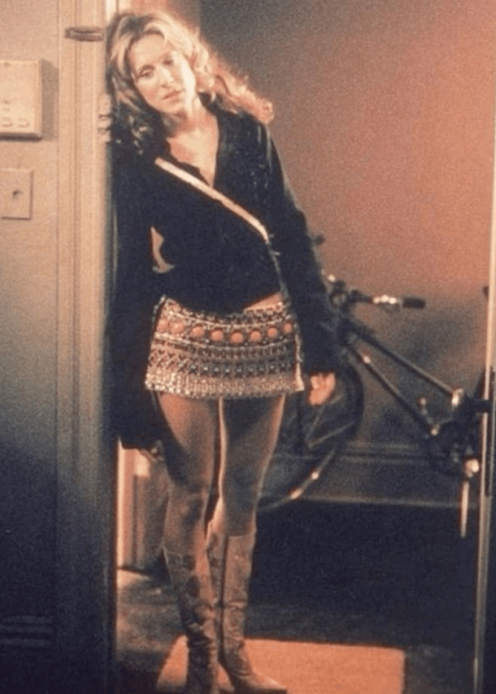 Sarah Jessica Parker - minissaia estampada, bota e blusa preta de manga longa - Carrie Bradshaw - outono - mulher em pé em uma sala - https://stealthelook.com.br