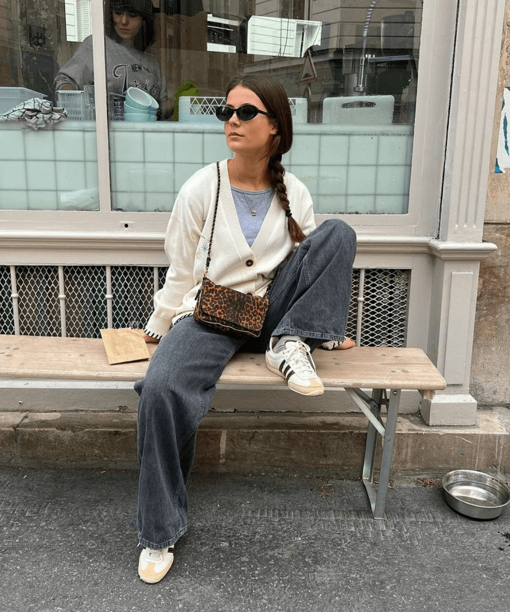 Manon De Velder - calça jeans, tênis, blusa e tricô off - tricô - inverno - mulher de óculos sentada em um banco segurando uma taça de vinho branco - https://stealthelook.com.br