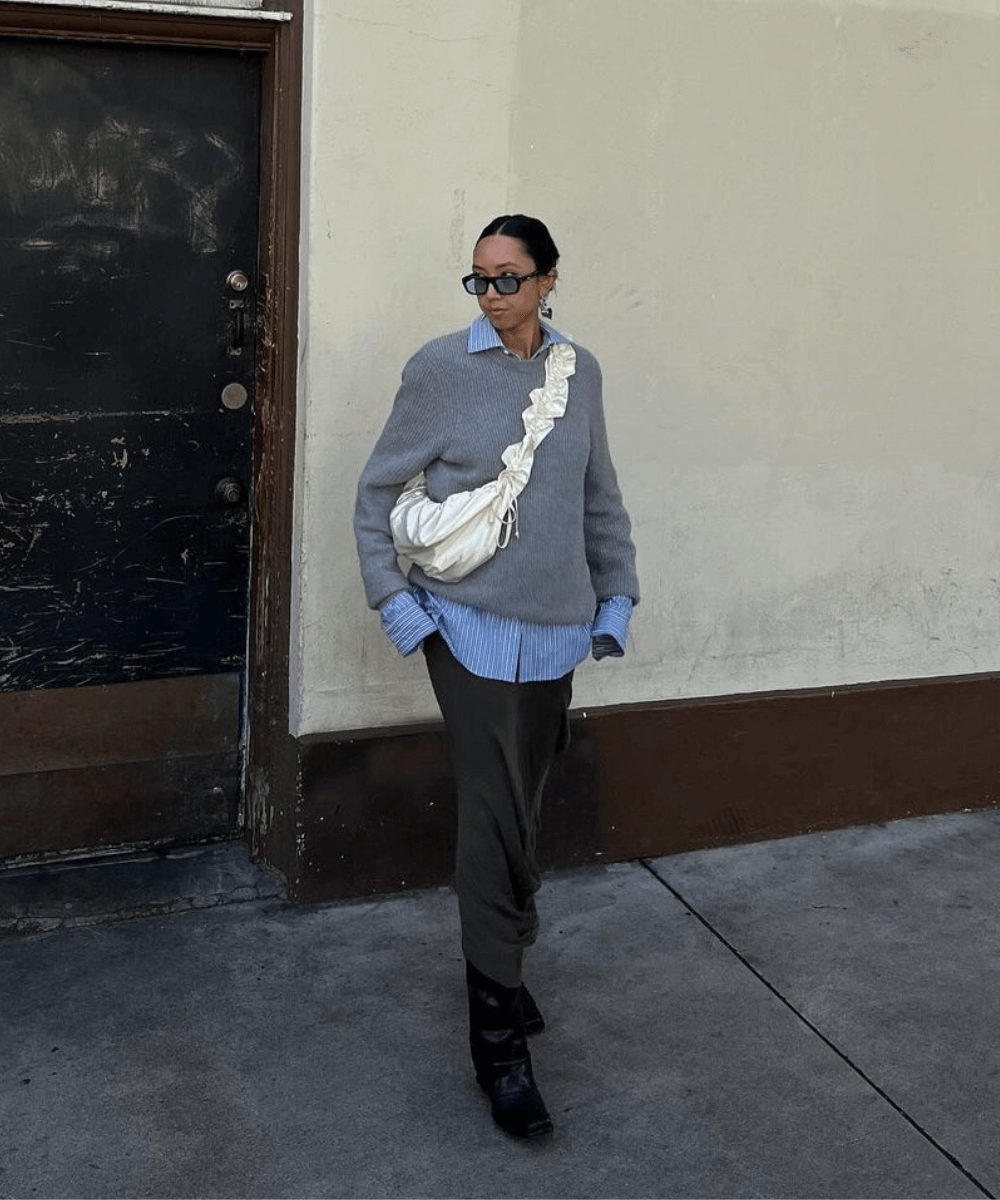 Stephanie Arant - saia longa, botas pretas, camisa azul e tricô cinza - tricô - inverno - mulher em pé na rua usando óculos de sol - https://stealthelook.com.br