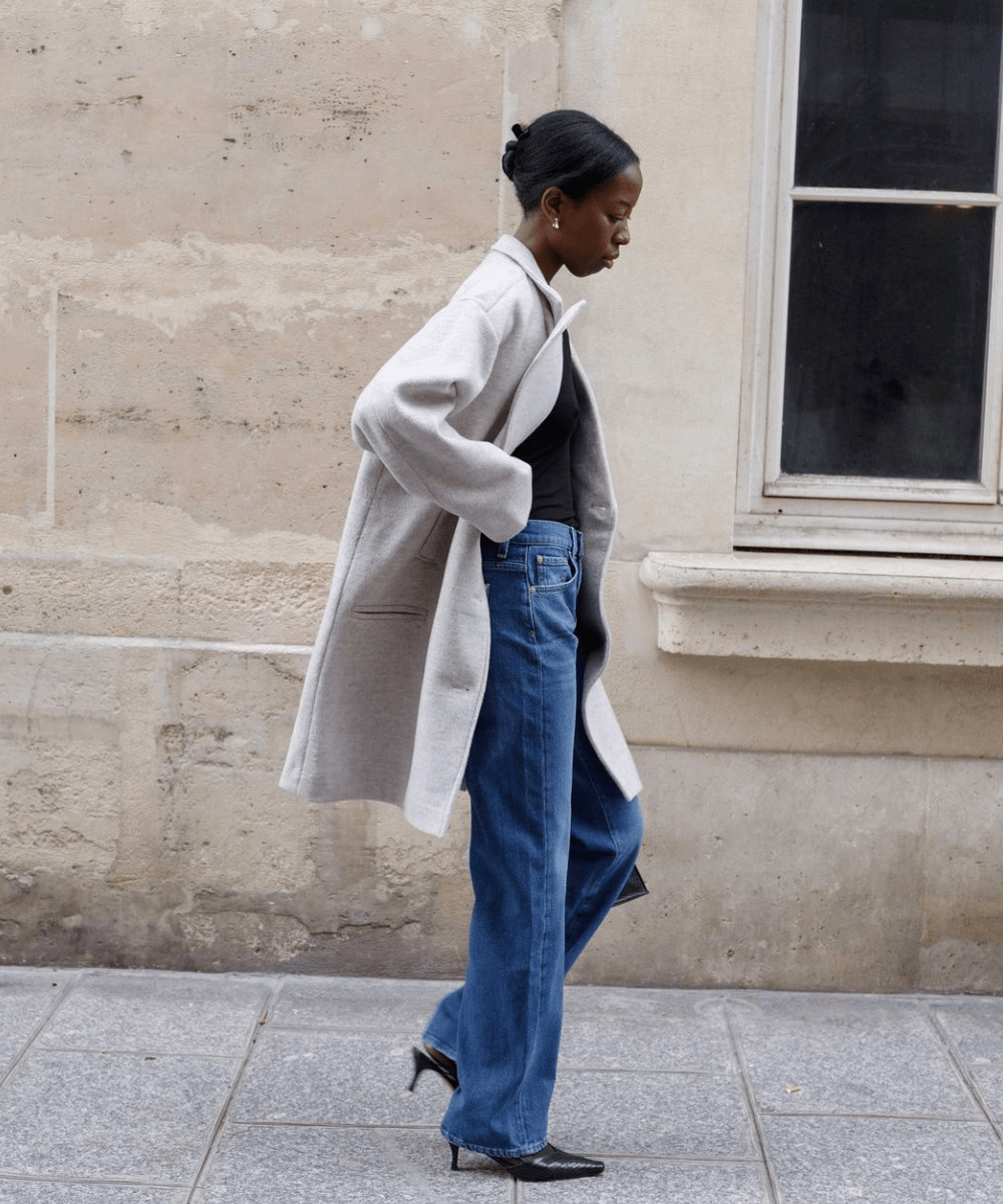 Sylvie Mus - calça jeans, scarpin, blusa preta e trench coat - Easy chic - outono - mulher negra andando na rua - https://stealthelook.com.br