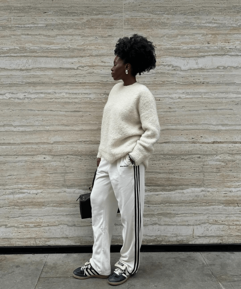Danielle Oreoluwa Jinadu - calça esportiva branca, tricô off white e tênis adidas - Easy chicI - inverno - mulher negra de lado em pé na rua - https://stealthelook.com.br