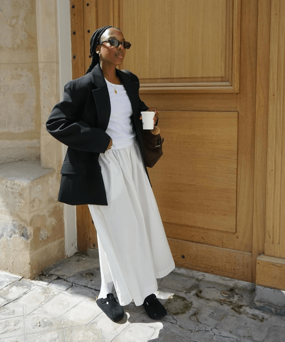 @taffymsipa - saia longa, blusa preta, blazer oversized preto, óculos de sol e clog preto - sapato tendência de 2024 - outono - mulher negra em pé na rua usando óculos de sol - https://stealthelook.com.br