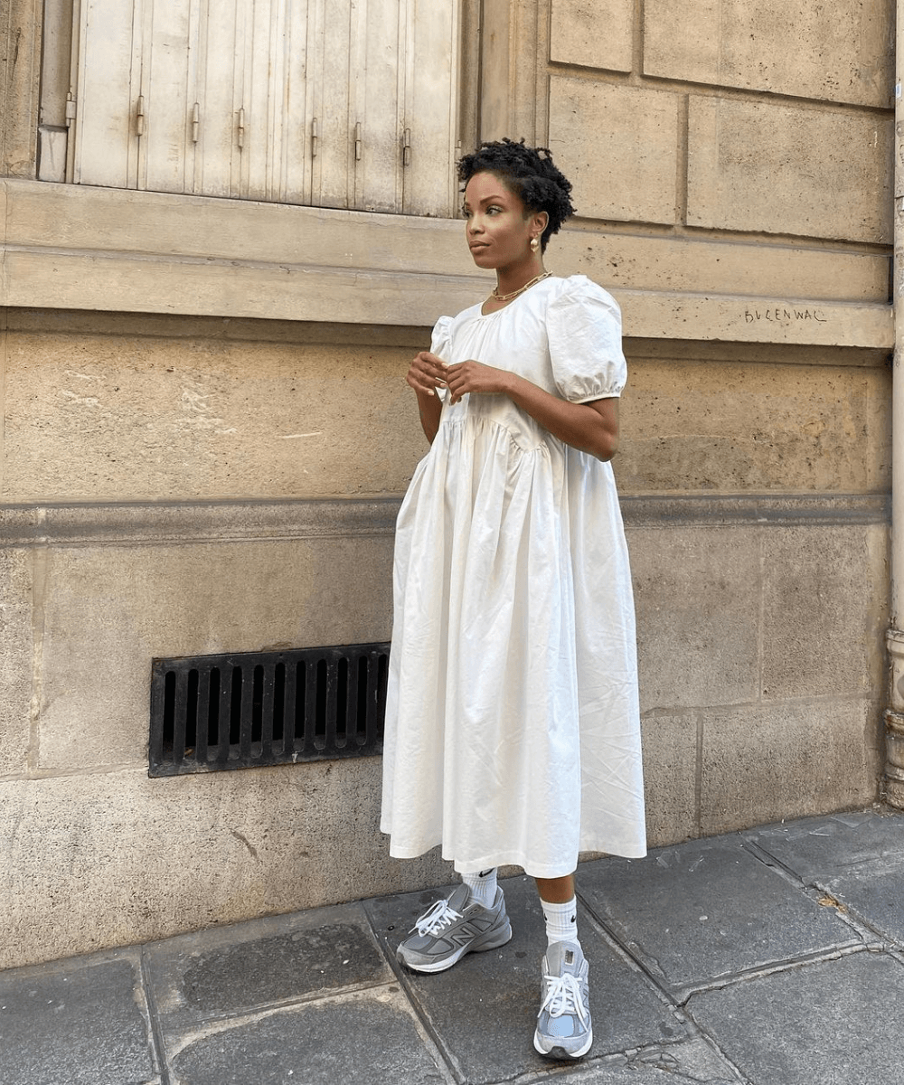 Ellie Delphine - vestido branco midi e tênis - vestido estiloso - verão - mulher negra em pé na rua - https://stealthelook.com.br