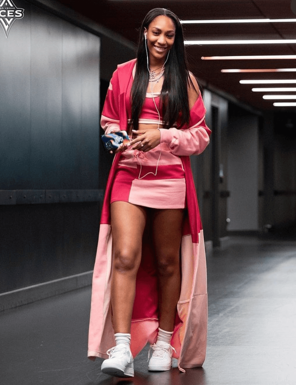 A'ja Wilson - conjunto de minissaia, top e casaco rosa longo - WNBA - outono - mulher negra sorrindo andando - https://stealthelook.com.br