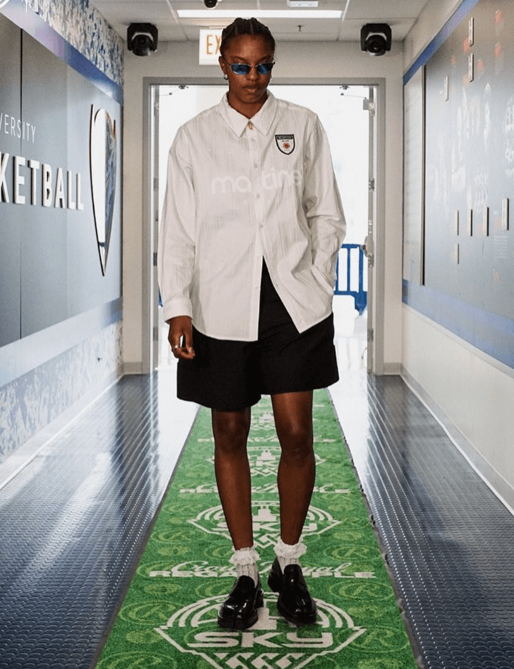 Diamond DeShields - bermuda preta, camisa branca oversized e tênis preto - WNBA - verão - mulher andando de óculos de sol - https://stealthelook.com.br