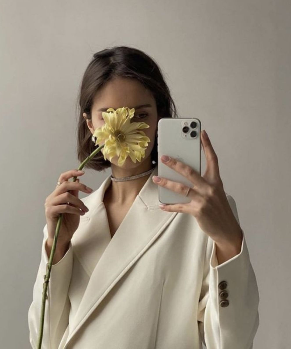 N/A - blazer oversized off white - aplicativos de edição - primavera - mulher em pé tirando foto segurando uma flor amarela na frente do rosto - https://stealthelook.com.br