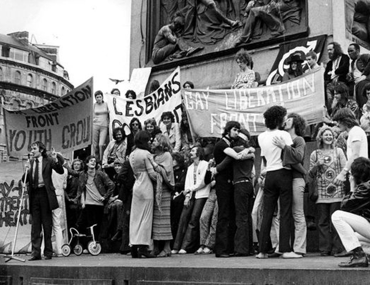 Imagem em preto e branco de um protesto da década de 1970. Os participantes exibem cartazes de movimentos de liberação gay e lésbico. Dia do Orgulho LGBTQIA+