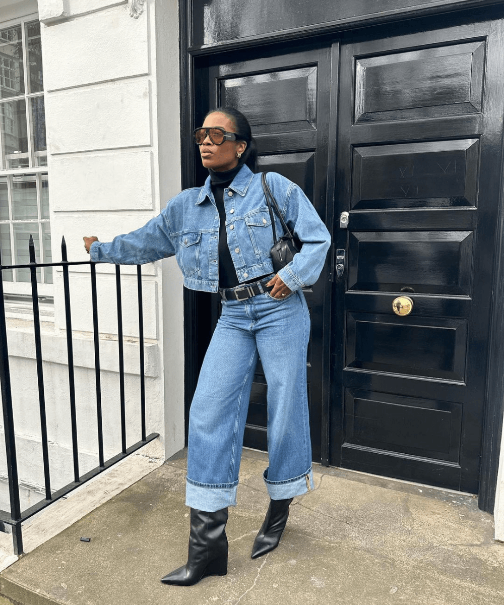 @nlmarilyn - calça jeans, blusa preta, jaqueta jeans e botas de cano longo pretas - looks para festa junina com calça jeans - inverno - mulher negra em pé na rua usando óculos de sol - https://stealthelook.com.br