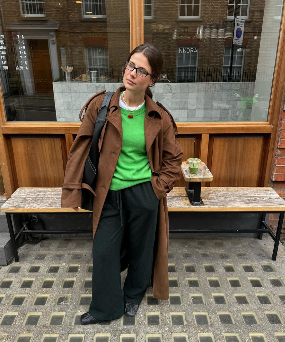 Manon De Velder - calça preta de moletom, tricot verde, sobretudo caramelo e sapatilhas - looks com calça preta - inverno - mulher morena em pé na rua usando óculos de grau - https://stealthelook.com.br