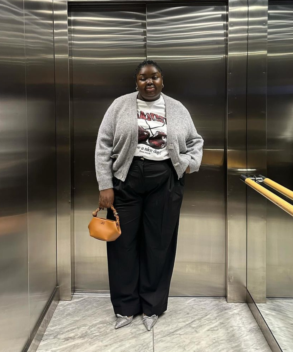 Abisola Omole - calça preta, tshirt, casaco cinza e scarpin prateado - looks com calça preta - inverno - mulher negra em pé dentro de um elevador - https://stealthelook.com.br