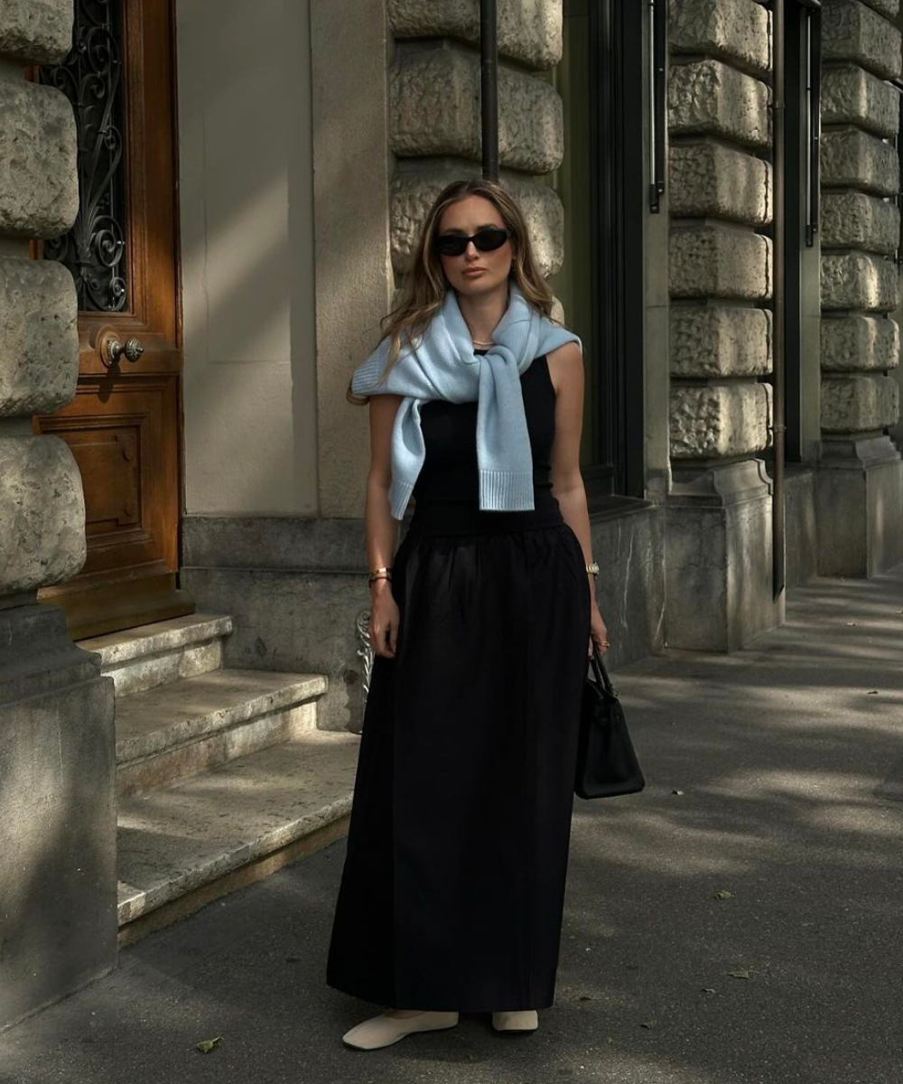 Olivia Faeh - vestido preto, trico azul, óculos escuros e sapatilhas - vestido elegante e estiloso - primavera - mulher de óculos em pé na rua - https://stealthelook.com.br