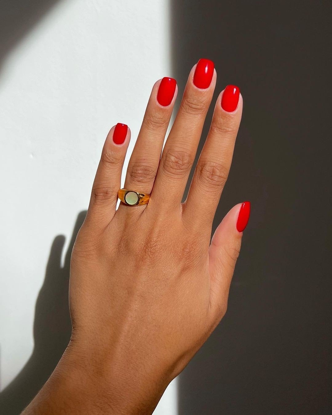 Unhas esmaltadas em vermelho vibrante, tendência forte na moda atual de manicure. Anel com design minimalista e detalhes em resina, acrescenta um toque moderno e elegante. Estilo clean e sofisticado, ideal para ocasiões diversas.