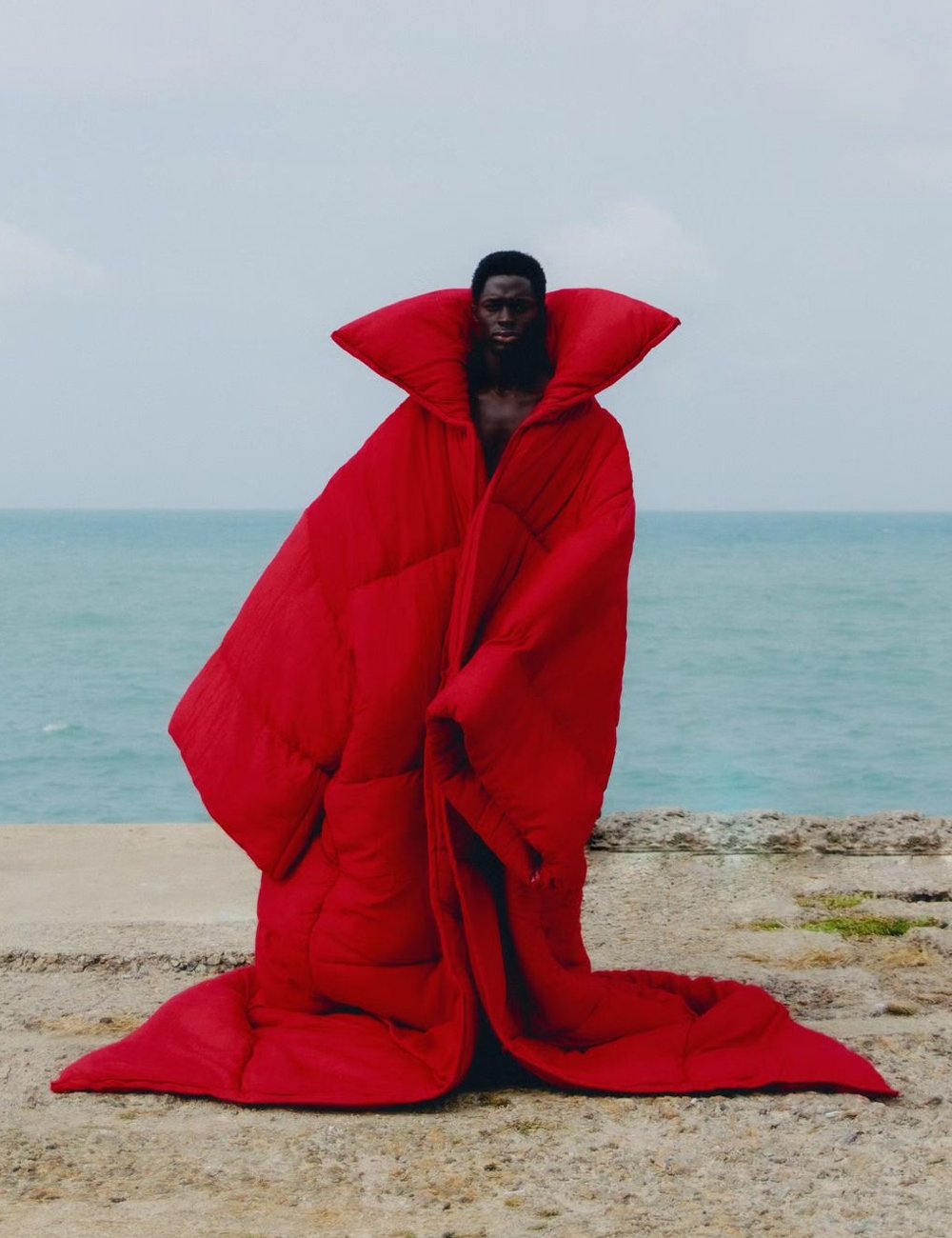 Pessoa vestindo um casaco oversized vermelho com estilo acolchoado. Peça de roupa volumosa e ousada, criando uma silhueta dramática. Tendência futurista e arrojada na moda contemporânea. Marcas autorais.