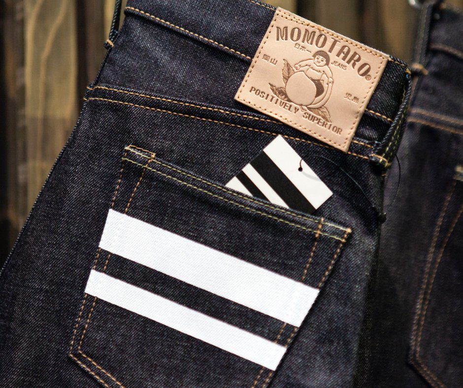 Jeans da marca Momotaro, destacando-se pelo estilo clássico de alta qualidade e pelo detalhe das listras brancas na parte traseira do bolso. Ideal para moda urbana e casual, símbolo de durabilidade e sofisticação.