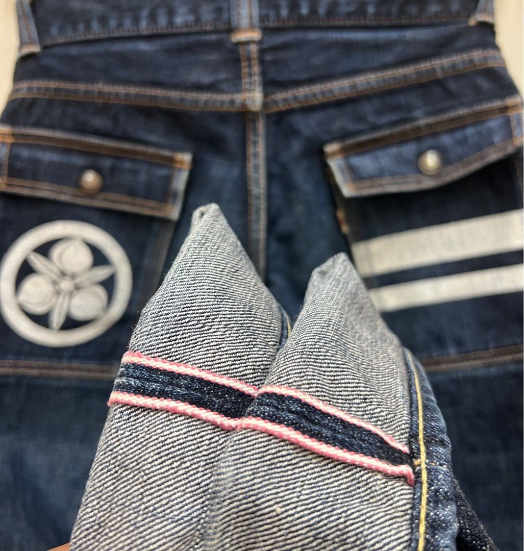 Close-up de detalhes em calças jeans artesanais, destacando estilo tradicional japonês com costura selvedge e bolsos duplos. Tendência em moda denim de alta qualidade e customização, ideal para admiradores de moda retrô e personalizada.