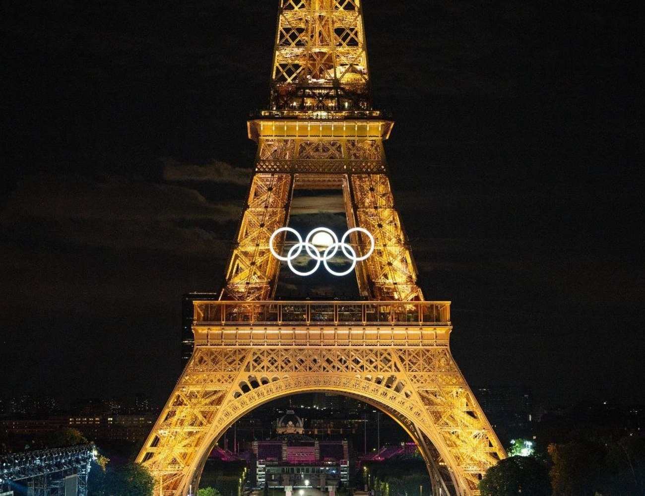 Imagem da Torre Eiffel iluminada à noite, exibindo os anéis olímpicos. Olimpíadas 2024.