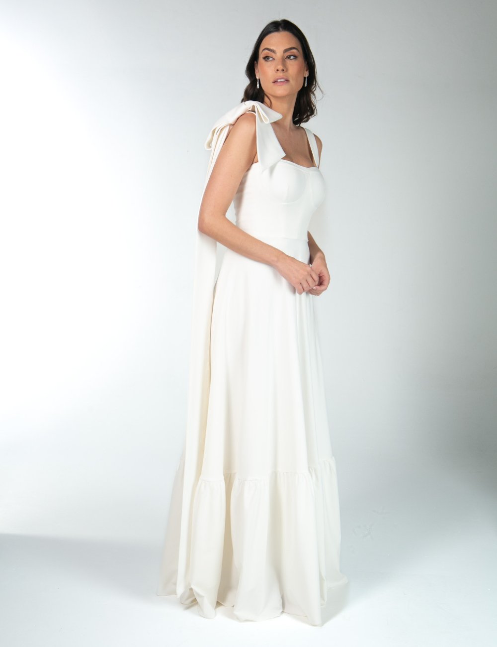 Vestidos de noiva com design elegante, destacando alça com laço decorativo. Forte tendência minimalista e de moda nupcial, perfeito para eventos formais. O caimento solto até os pés realça a sofisticação e o estilo clássico.