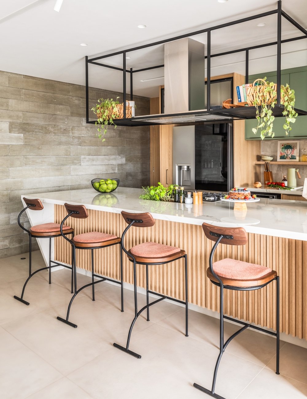 Cozinha moderna com design minimalista. Bancada branca com banquetas altas de estrutura metálica e assentos almofadados em tom terroso. Estante suspensa preta com plantas e livros. Detalhes em madeira clara e armários verde-menta.