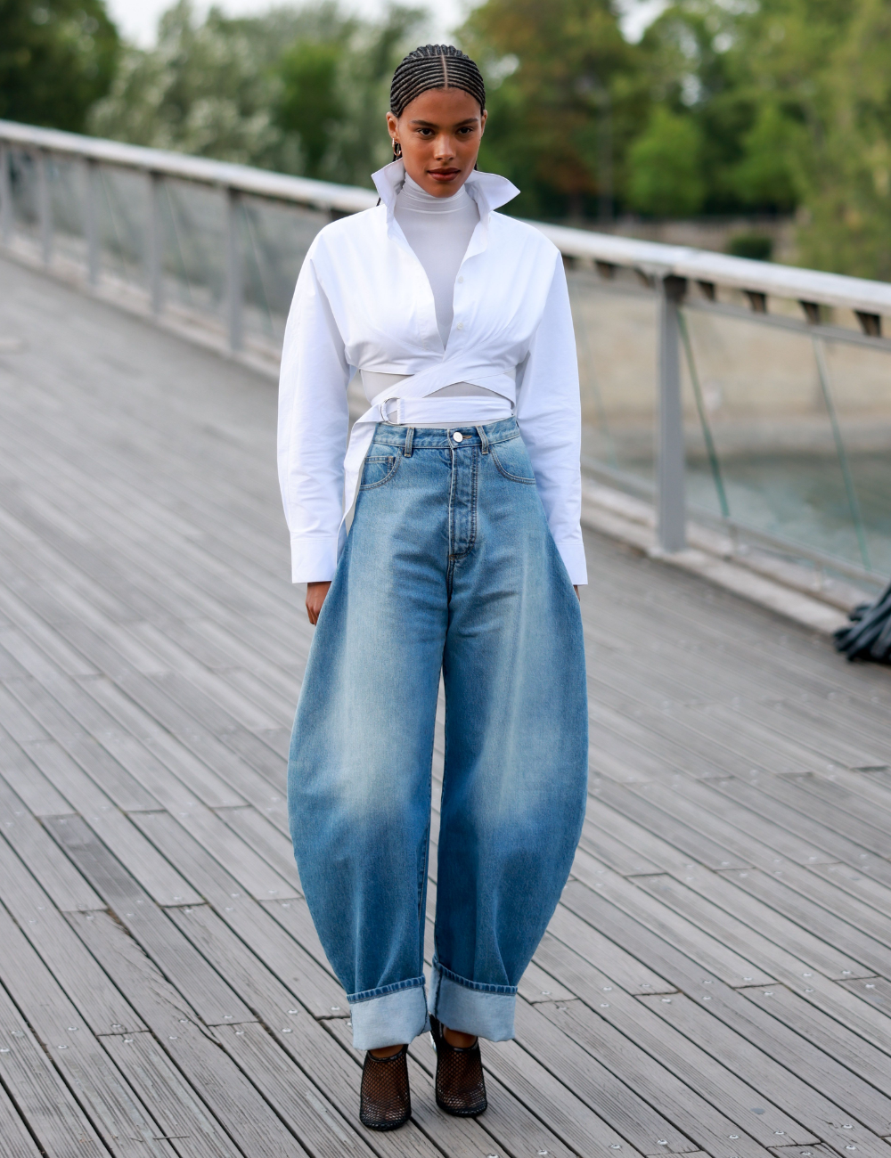 Mulher usa camisa branca e calça jeans barrel de pernas amplas.