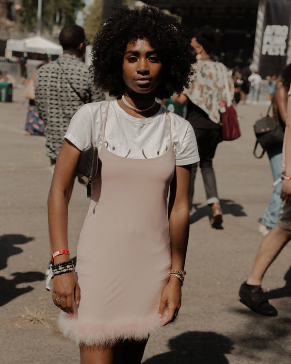 Mulher usando vestido rosa claro com alças, sobreposto a uma camiseta branca.