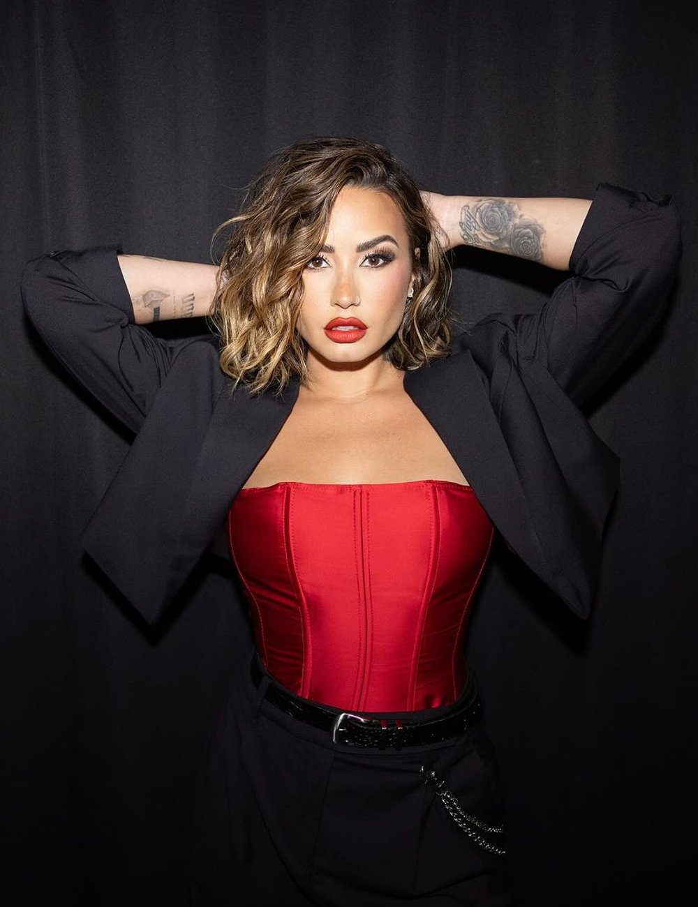 Demi Lovato com maquiagem marcante e cabelo ondulado. Estilo combina elementos audaciosos e elegantes, refletindo tendências de moda contemporâneas de ousadia e sofisticação, ideais para eventos noturnos.