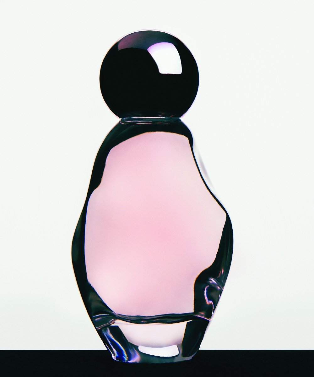 Frasco de perfume em forma elegante, com vidro translúcido em tom rosa e tampa preta brilhante. Design sofisticado, ideal para amantes de fragrâncias e tendências de moda que valorizam a estética moderna e minimalista. kylie jenner