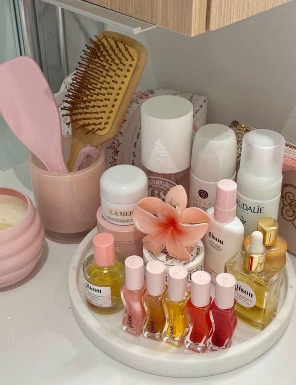 Imagem de um organizador de maquiagem. Produtos incluem esmaltes, cremes e perfumes, destacando um pincel e uma escova de cabelo. Tendência minimalista e estética clean com foco em cuidados pessoais e bem-estar.