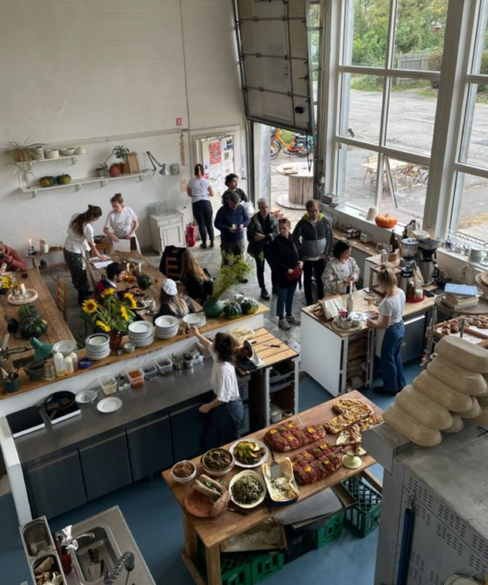 Em uma cozinha moderna e espaçosa, pessoas vestem roupas casuais, com predominância de jeans, calças largas e camisetas. A combinação de tons neutros e estilos relaxados é destaque, refletindo tendências atuais de conforto e simplicidade na moda.