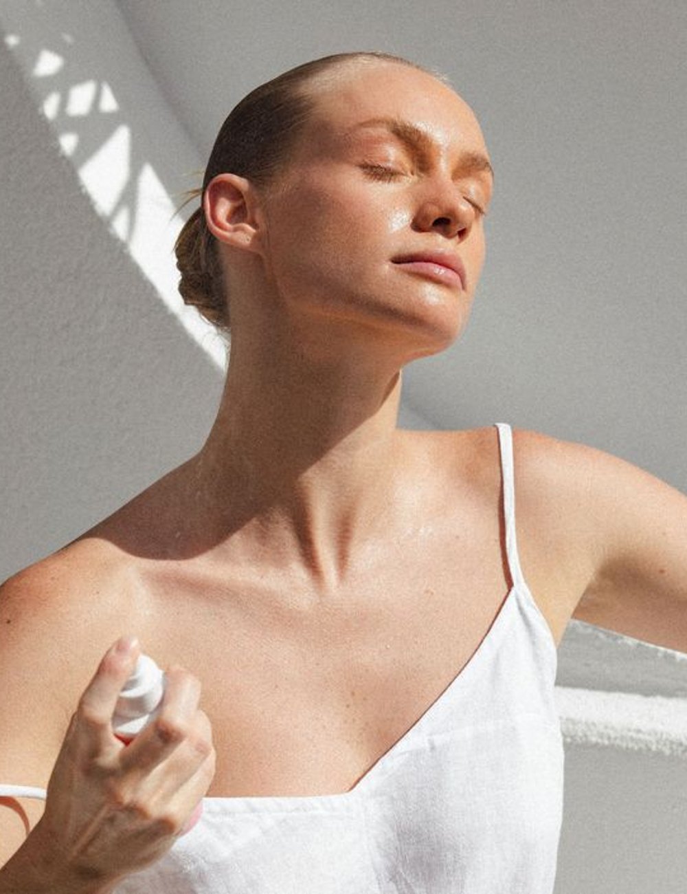 Mulher usando vestido branco de alças finas, estilo minimalista. A pele bronzeada destaca a tendência de cuidar da pele ao ar livre. A simplicidade e elegância do look fazem parte das tendências de moda primavera/verão. Soprar canela.