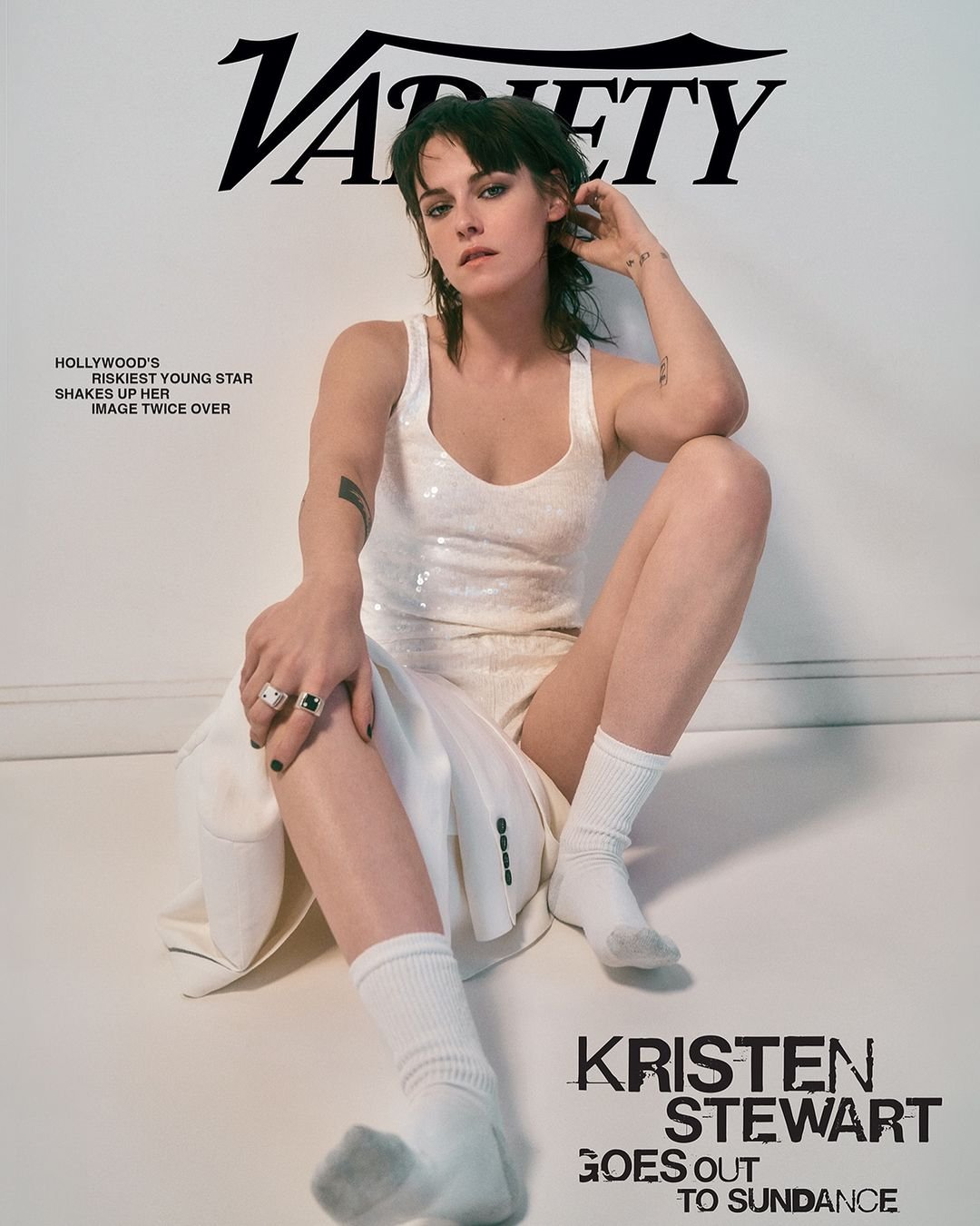 A capa da revista exibe uma pessoa vestindo um look casual e moderno, com um top branco brilhante, shorts brancos, jaqueta branca e meias brancas.