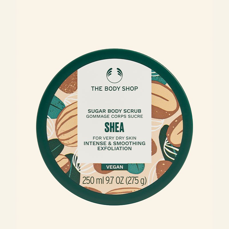 Esfoliante corporal de açúcar Shea da The Body Shop. Produto vegano para esfoliação intensa e suavizante, ideal para pele muito seca. Embalagem com design verde e ilustração de nozes. Conteúdo de 250 ml (275 g). cheirosa o dia todo