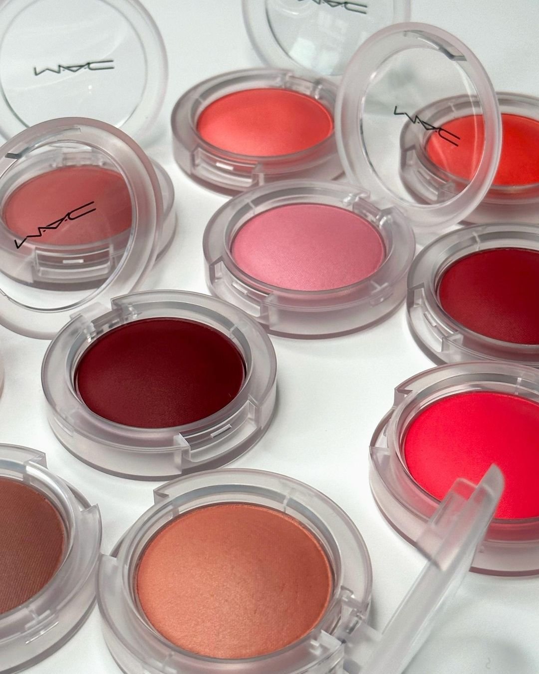 Imagem de diversos blushes em tons vibrantes e naturais, dispostos em embalagens transparentes da MAC.evidenciando tendência de cores variadas e acabamento acetinado para um visual moderno e versátil. novidades de beleza