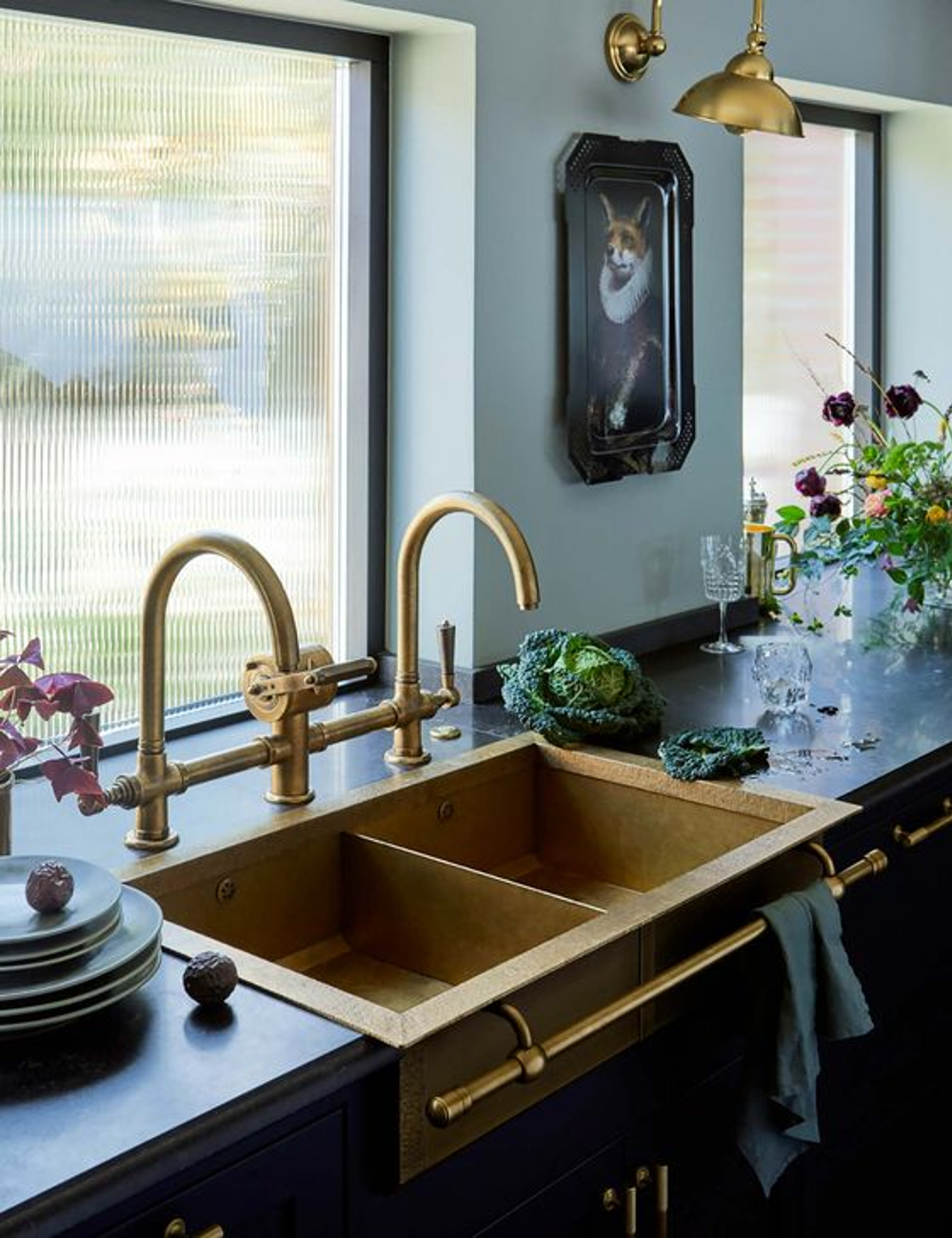 Foto de uma cozinha estilosa com detalhes de decoração luxuosos. A pia dourada e torneira de cozinha combinam com os pendentes modernos também em dourado.