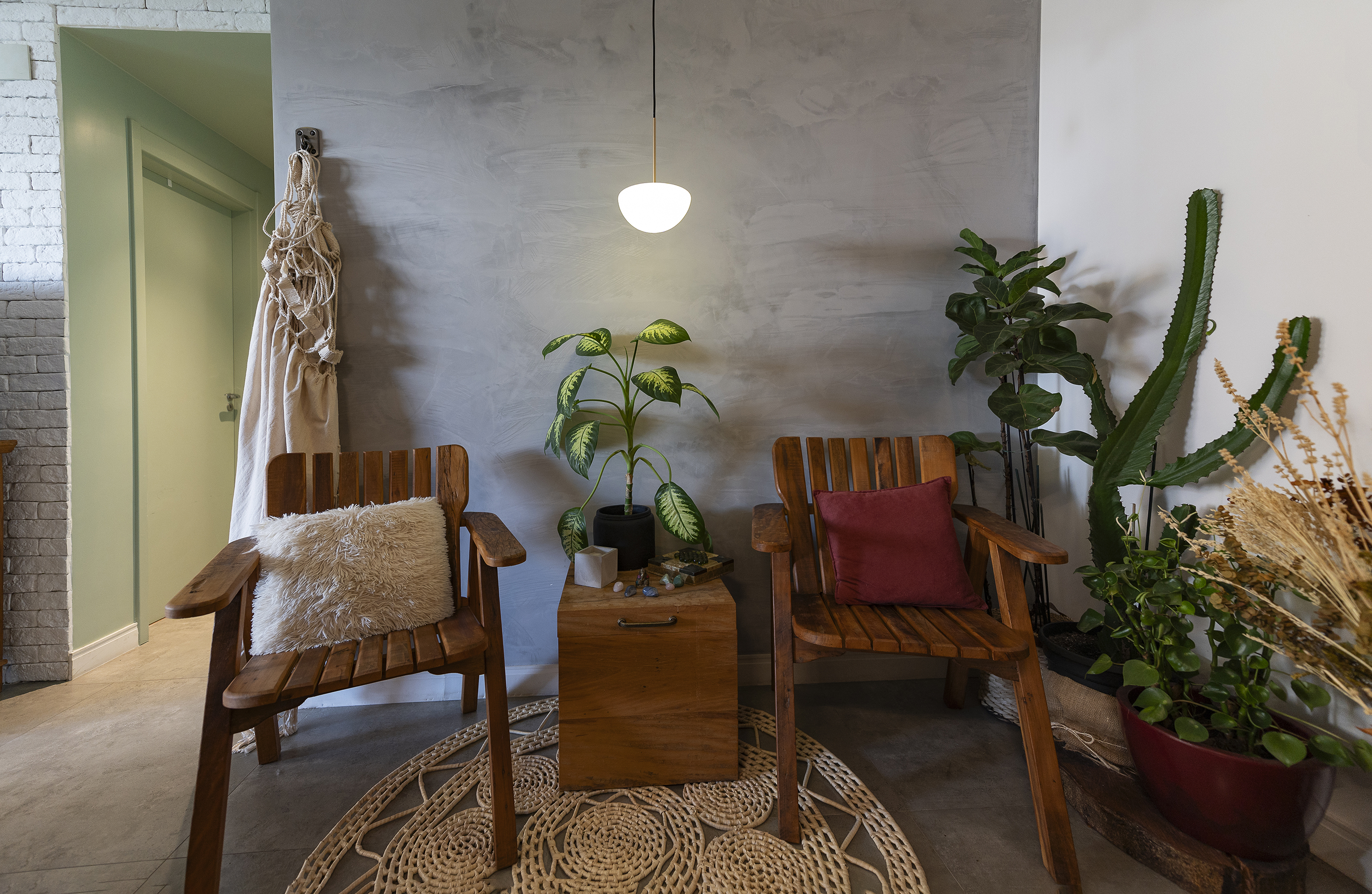 Cadeiras de madeira com almofadas em apartamento decorado com plantas variadas.