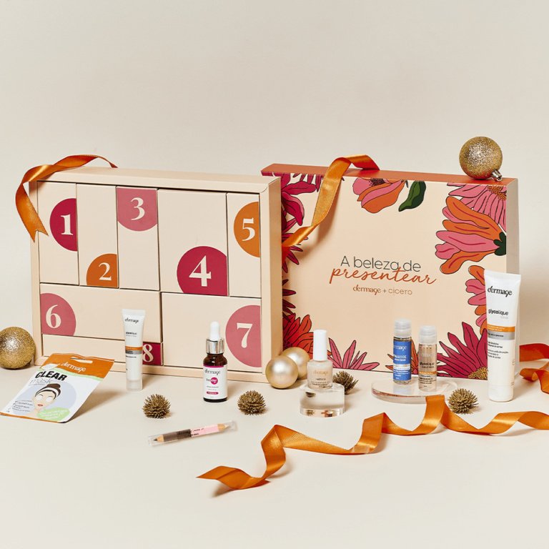 Caixa de calendário do advento com produtos de beleza variados, fitas laranja e decoração natalina ao redor.