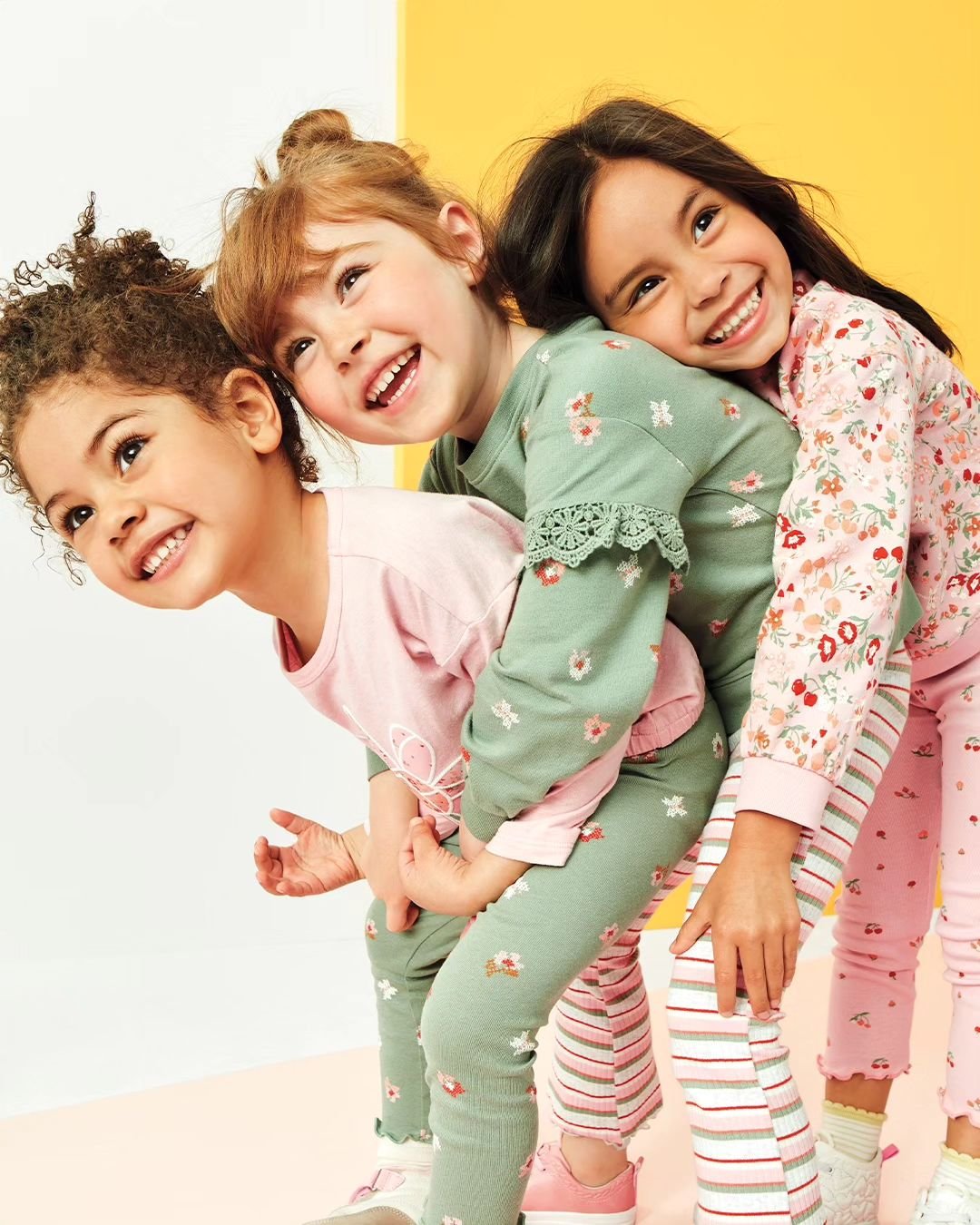 Crianças sorrindo usando pijamas floridos e coloridos em pose divertida. Roupa de bebê.