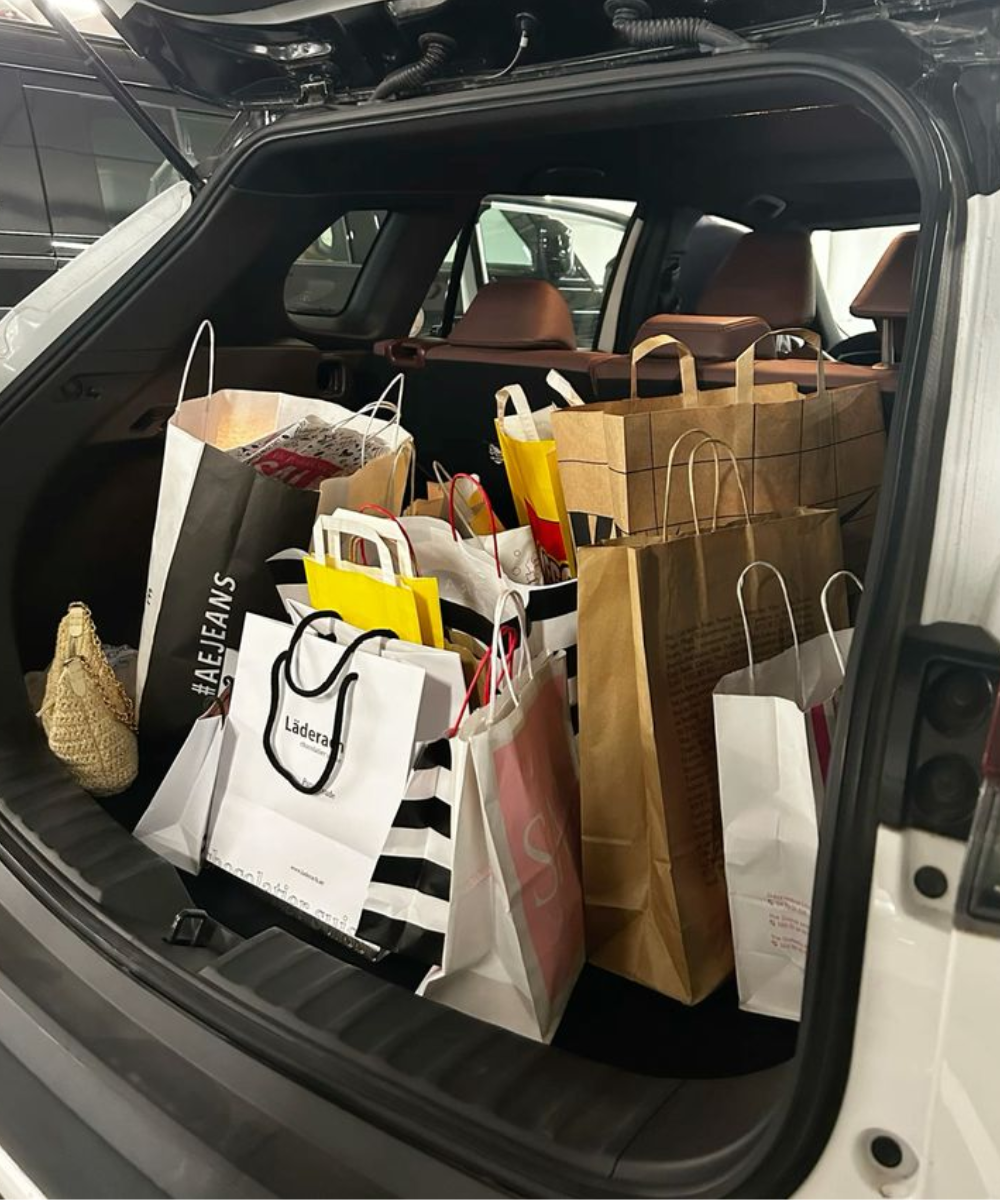 Mala de carro cheia de sacolas de compras de moda. Presença de marcas variadas indica tendências de consumo atual, com destaque para o estilo casual e moderno, valorizando a diversidade no vestuário.