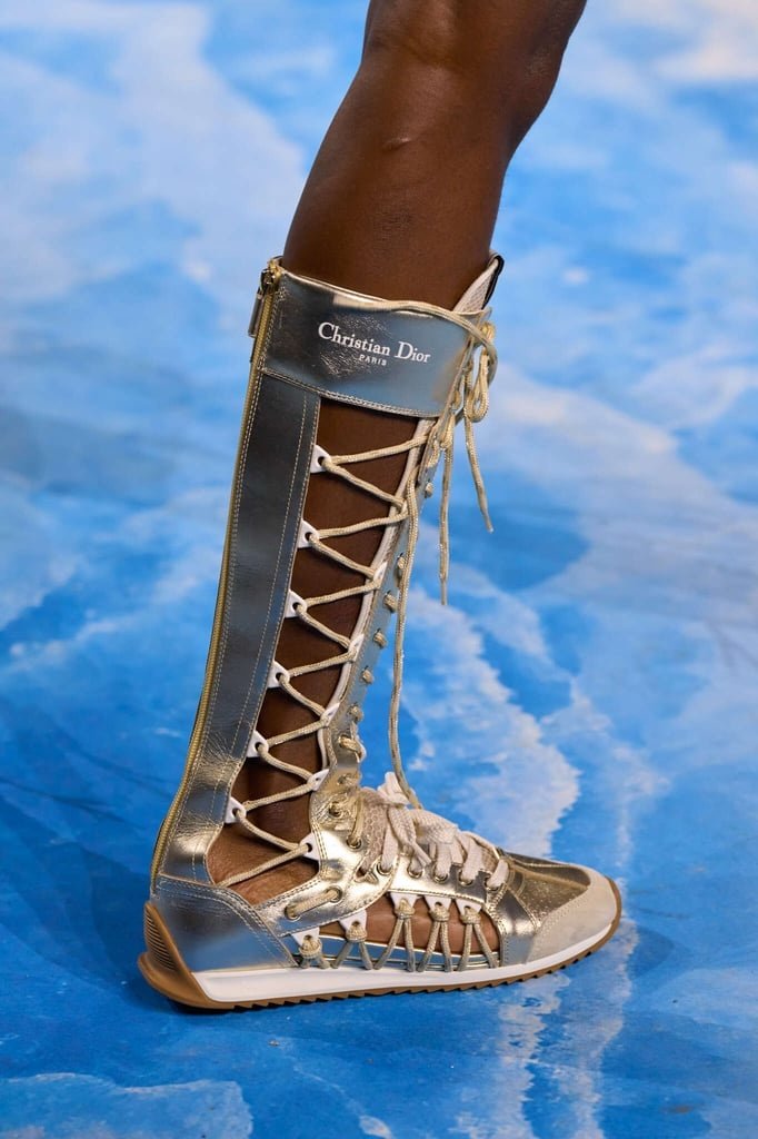 Bota metálica estilo boxing boot da Christian Dior, com cadarços e detalhes únicos, em fundo azul.