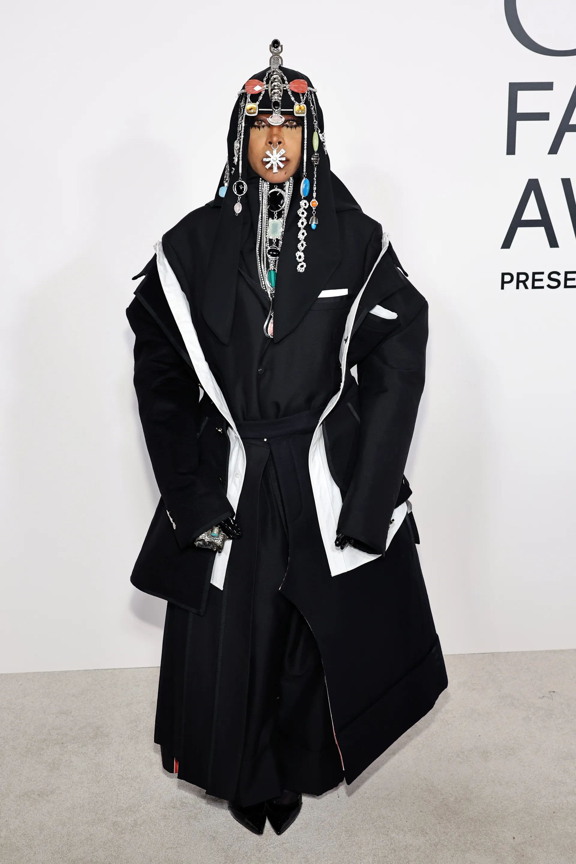 Traje de gala preto com ornamentos metálicos e joias, destaque no CFDA Fashion Awards 2024.