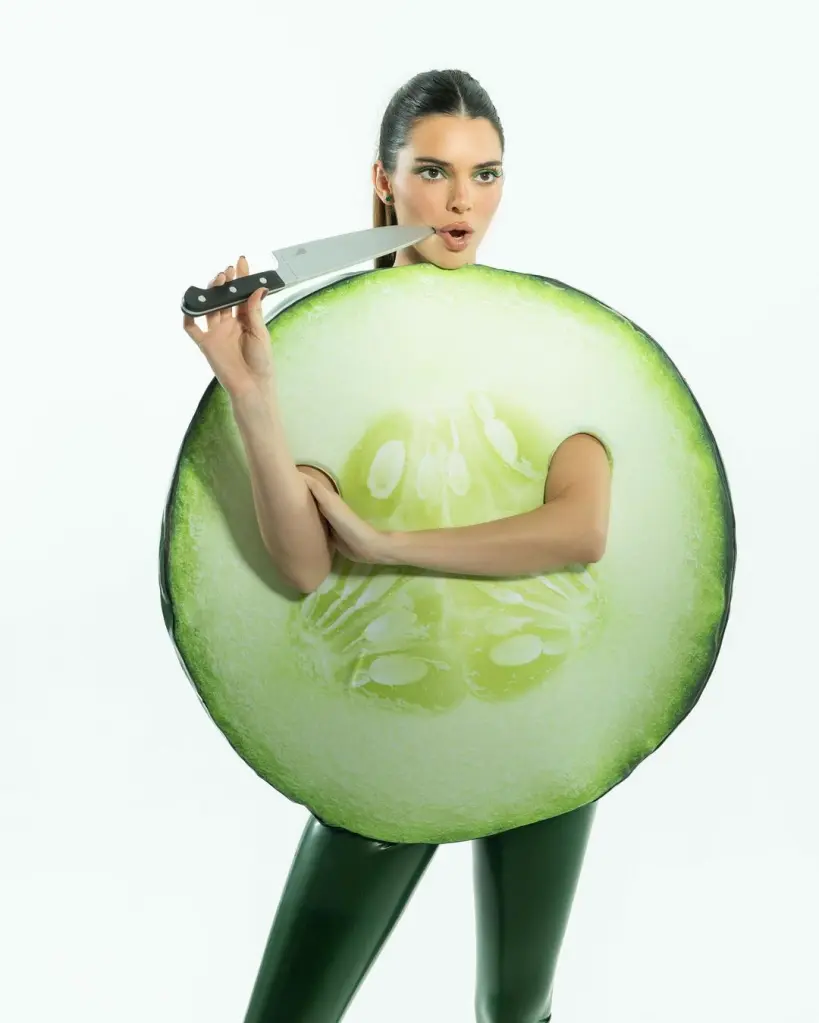 Kendall em fantasia de fatia de pepino segura faca. Fantasias das Kardashians.