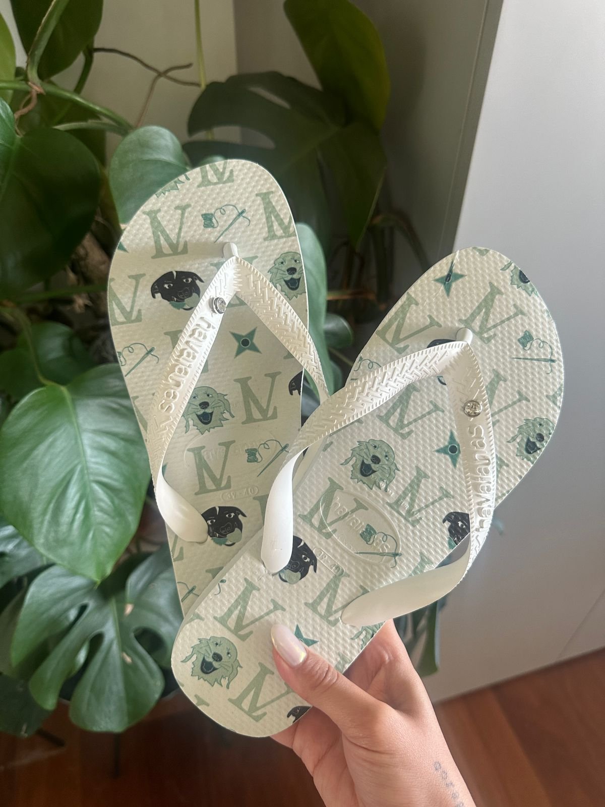 Chinelo branco estampado com padrões gráficos e desenhos de cães do casamento da Lela Brandão. Estilo casual ideal para o verão, realçando um design moderno e divertido.