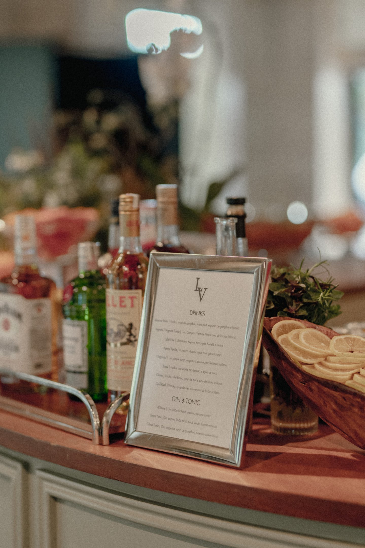 Imagem de um bar elegante com garrafas de bebidas diversas e um cardápio em moldura sofisticada. Composição moderna destaca tendências minimalistas na decoração de ambientes de coquetéis, enfatizando elegância e simplicidade.