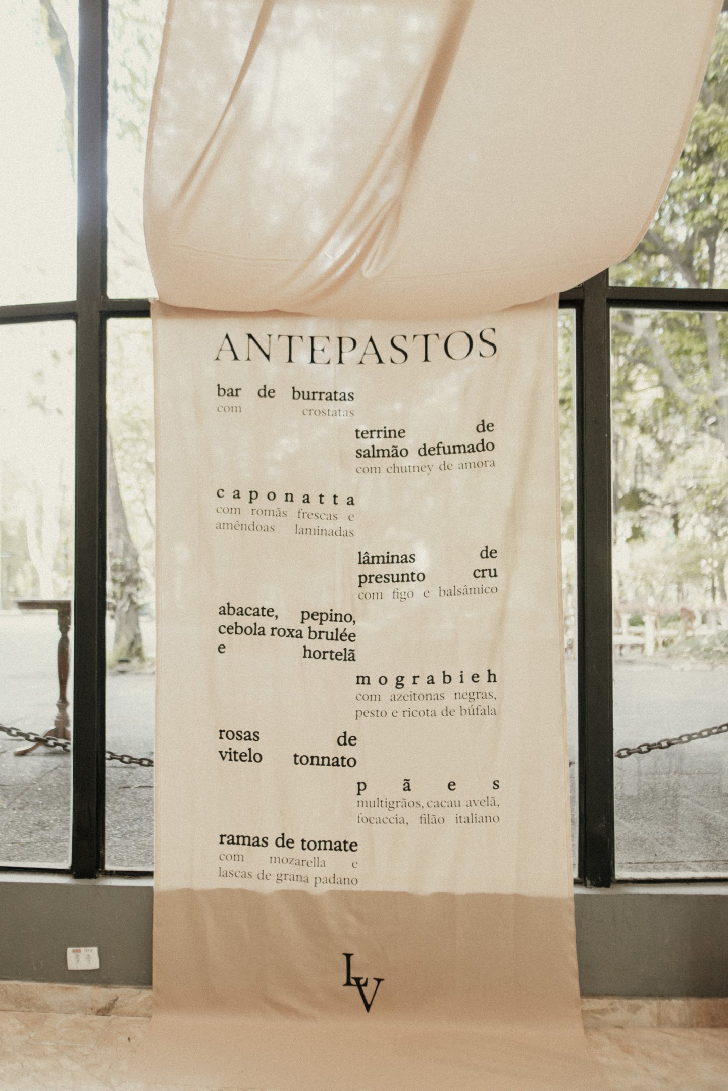 Imagem de um menu de antepastos, elegante e minimalista, destacando-se pela tipografia moderna em fundo bege suave. A apresentação remete a um ambiente sofisticado e contemporâneo, perfeito para eventos de alto padrão.