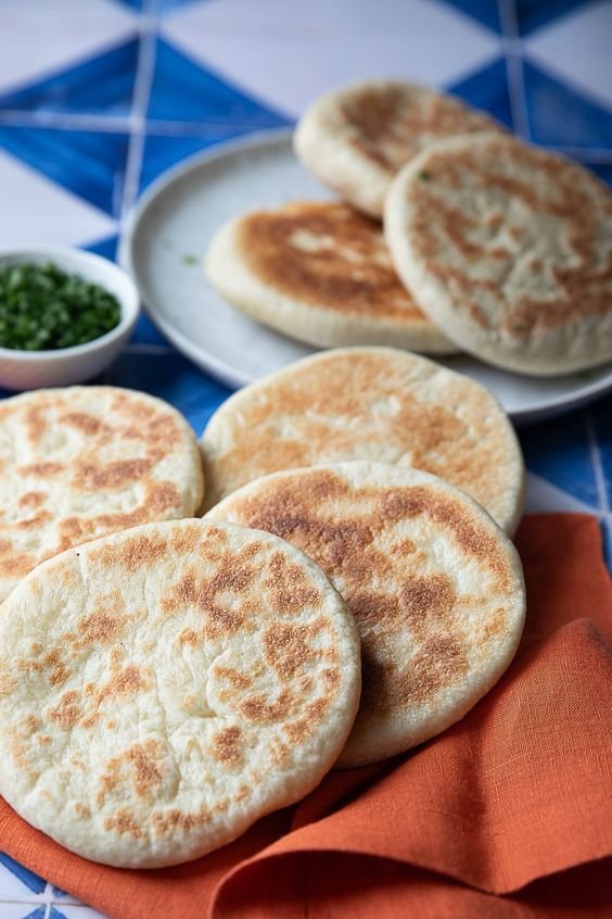 Pães circulares, sugestão de pão caseiro saudável, dispostos sobre guardanapo laranja.